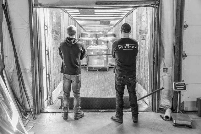 Two Winndom mattress employees looking at a loaded mattress delivery truck