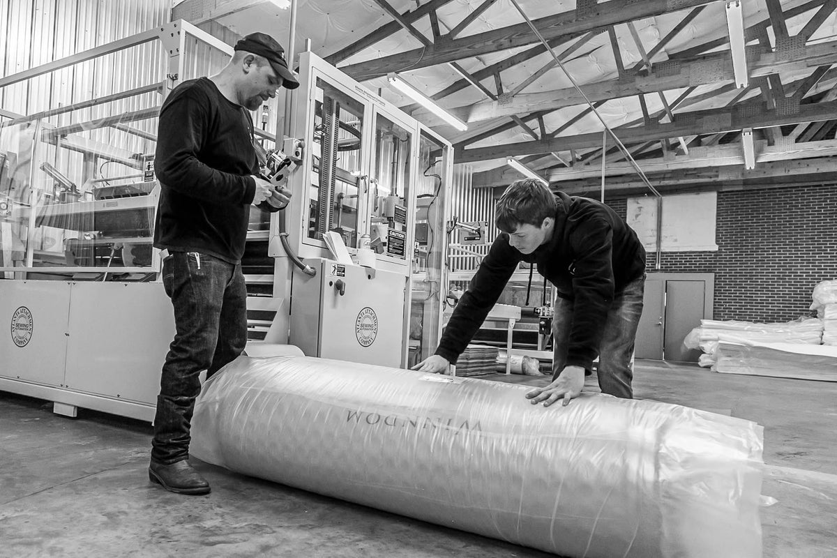 Two men working with a Winndom Mattress in an industrial setting