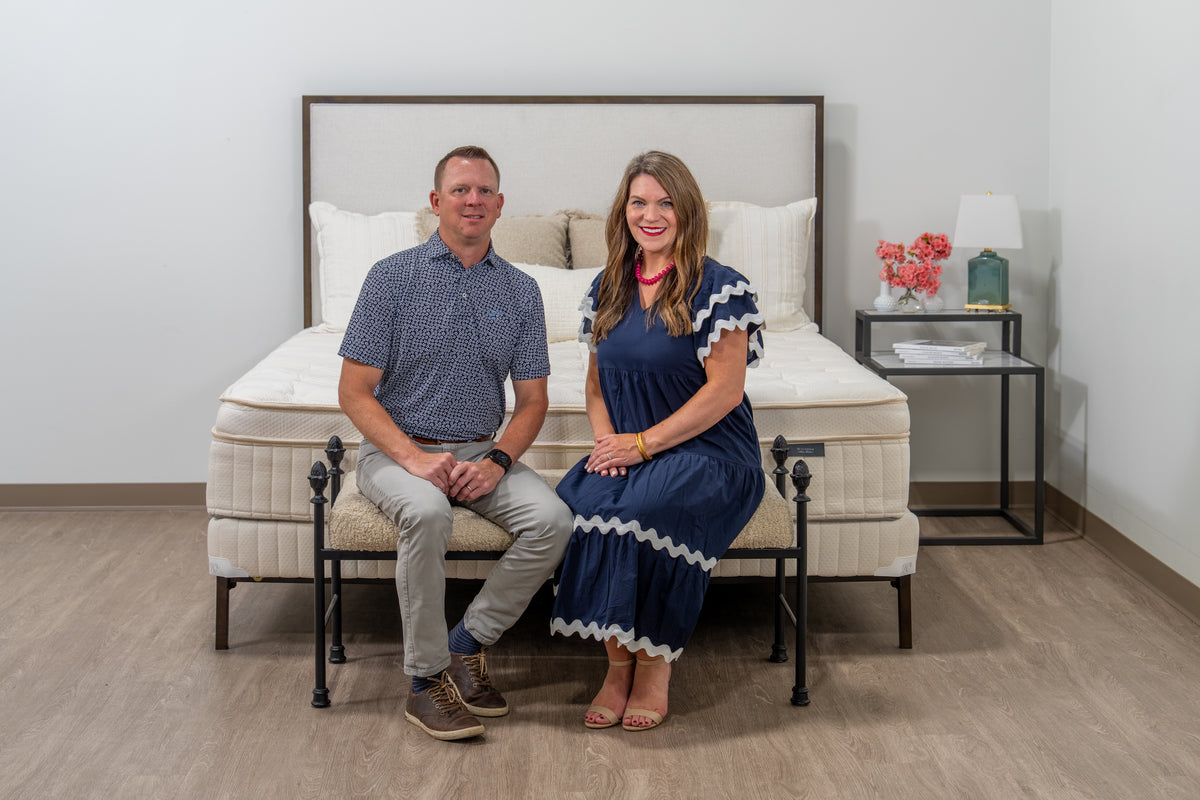 Man and woman sitting on a bed in a bedroom setting