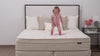 Girl jumping on Winndom mattress and puppy laying on Winndom mattress