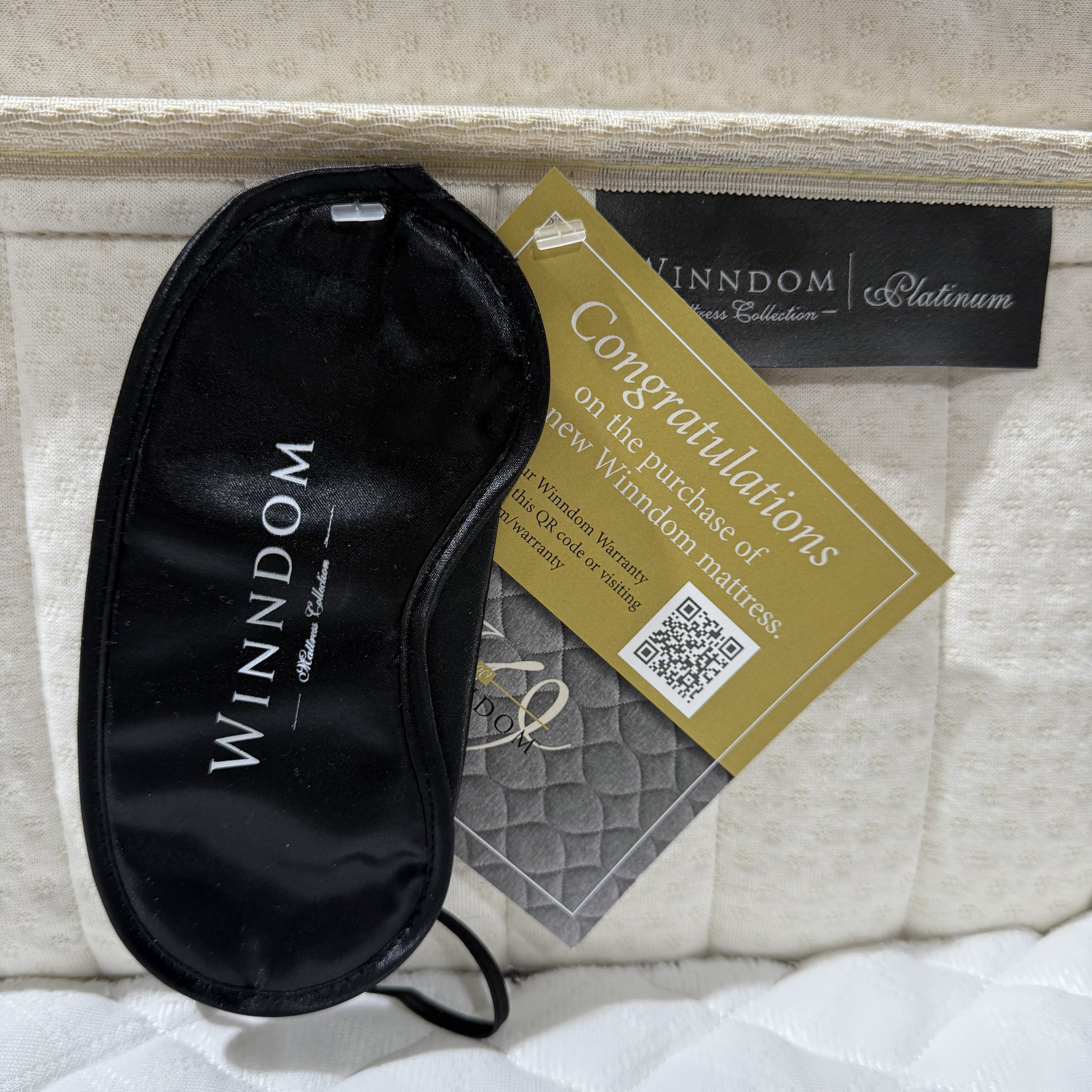 Black sleep mask with Winndom branding on a mattress with a gold tag.